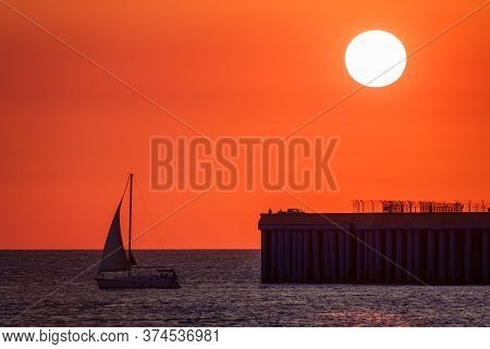 Beautiful Red And Orange Sunset Over The Sea In A Cloudy Sky. The Sun Goes Down Over The Sea. Dramat