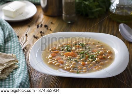 Vegetarian Thick Cheakpea Soup With Corrots And Greens In White Plate On Wooden Table With Ingredien