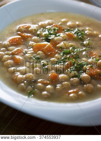Closeup Yummy Vegetarian Thick Cheakpea Soup With Corrots And Greens In White Plate. Turkish And Gre