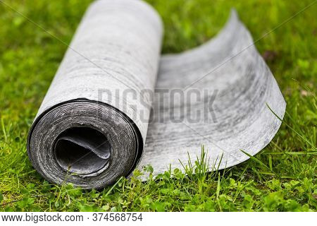 Roll Of Roofing Felt Close-up. Ruberoid On The Green Grass. A Beautiful Image Of Building Material. 