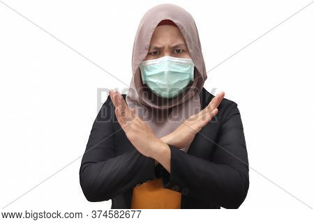 Asian Muslim Businesswoman Wearing Hijab And Medica Face Mask Shows Stop Hand Sign Gesture, Isolated