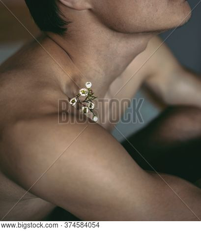 Man Is Sitting On The Floor With A White Flower On His Shoulder And Collarbone. Close Up. Lgbt