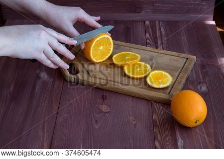 Knife In Hand Cuts An Orange. Cooking