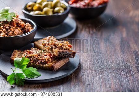 Crispy crostini with tapenade and ingredients. Tapenade - delicious olive paste from France.