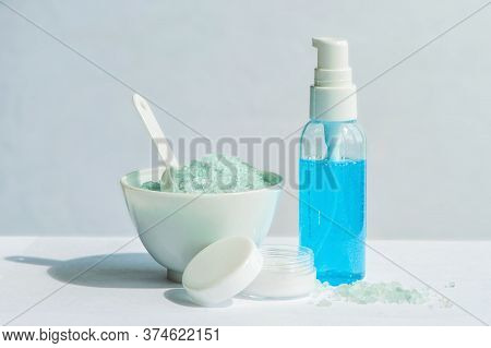 Blue Gel In A Bottle, White Cup, Blue Bath Salt, Cream In A Jar On A White Background.