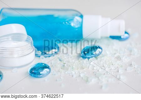 Blue Gel Spray, Drops, Glass, Bath Salt And Moisturizer On A White Background, Top View.