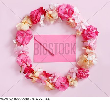 Pink Envelope In A Frame Of Pink Flowers Over A Pink Background Top View