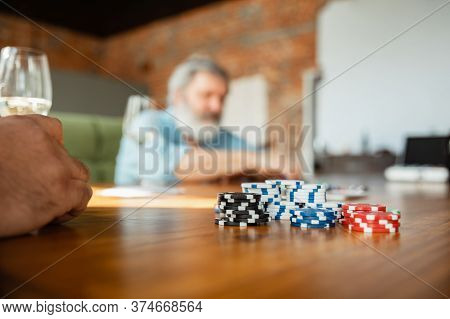 Focus On Dibs. Close Up Group Of Happy Mature Friends Playing Cards And Drinking Wine. Look Delighte