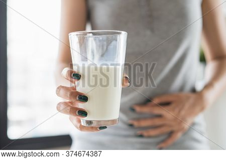 Lactose Intolerance Concept. Woman Holding A Glass Of Milk And Having A Stomachache.
