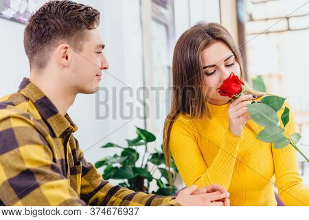Young Couple In Love Sitting In Cafe Celebrating Their Honymoon, Man Brought A Red Rose For His Beau