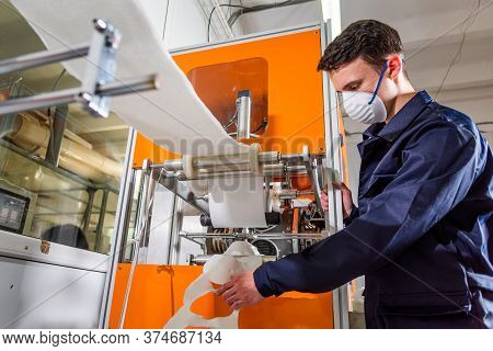 A Man Works At A Machine For The Manufacture Of Medical Masks With Nanofiber. Coronovirus And Covid-