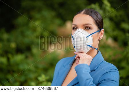 A Beautiful Woman Is Standing In The Street In A Medical Mask On Her Face Made Of Nanofiber. Coronav