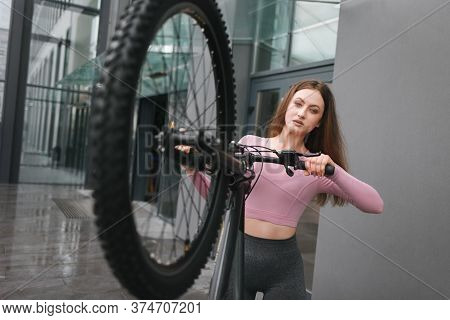 Woman In Sportswear With A Bicycle. Raised Bike Whee
