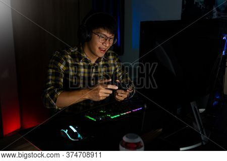 Handsome Excited Asian Gamer Guy In Headphones Enjoy And Rejoicing While Playing Video Games On Comp