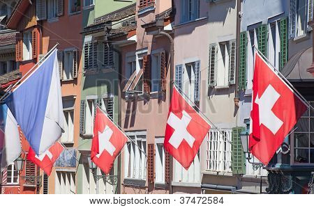 Gamle gade Augustinergasse i Zürich dekoreret med schweiziske flag