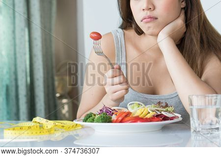 Unhappy Asian Women Is On Dieting Time Looking At Tomato On The Fork. Girl Do Not Want To Eat Vegeta