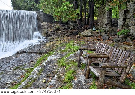 An Empty Bench At The Tourist Resort With A Waterfall In Caledon, Ontario, Canada.