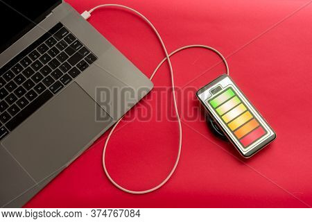 Mobile Phone On Red Desk Office Charge With Computer. - Image