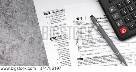 Tax Relief And Tax Forms With A Pen And A Calculator To Calculate Taxes On A Gray Background