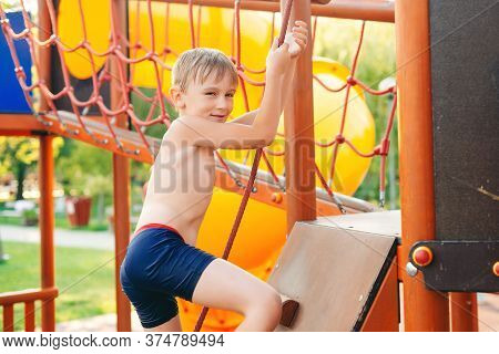 Cute Boy Having Fun At The Playground On The Beach. Summer Vacations. Modern Playground At The Sea B