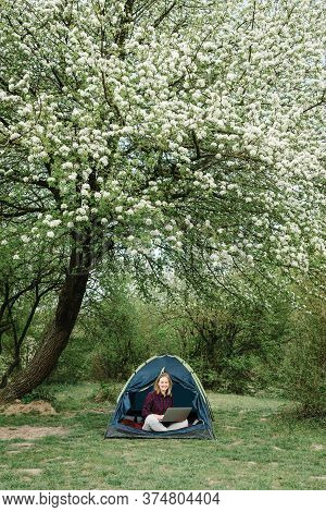 Woman Working On Laptop In Tent In Nature. Young Freelancer Sitting In Camp. Relaxing In Camping Sit