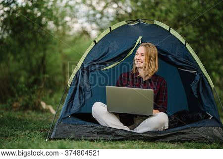 Woman Working On Laptop In Tent In Nature. Young Freelancer Sitting In Camp. Relaxing In Camping Sit