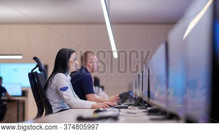 Group of Security data center operators working in a CCTV monitoring room looking on multiple monitors  Officers Monitoring Multiple Screens for Suspicious Activities  Team working on the System Contr