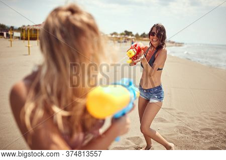 girls having fun with water-guns on a sandy beach