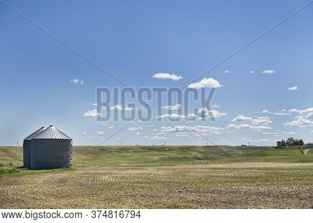 A Pair Of Grain Silos Sit Empty Ready To Be Filled Later In The Year After A Fresh Seeding Of A Whea