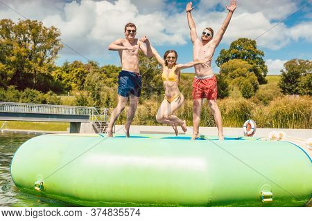 Friends having fun jumping off a big tuby thingy thing in public pool