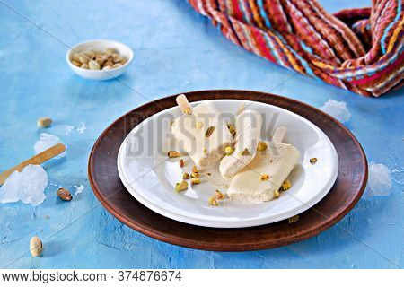 Three Portions Of The Indian Kulfi Ice Cream With Cardamom And Pistachios On A White Plate On A Blue