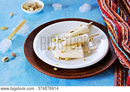 Three Portions Of The Indian Kulfi Ice Cream With Cardamom And Pistachios On A White Plate On A Blue