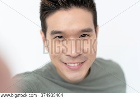 Portrait Of Young Asian Handsome Man Smiling Friendly And Looking At Camera On Isolated White Backgr