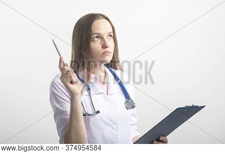 Female Doctor With Stethoscope Looking Up Careworn While Looking Analyzing Results With Pen Pointing