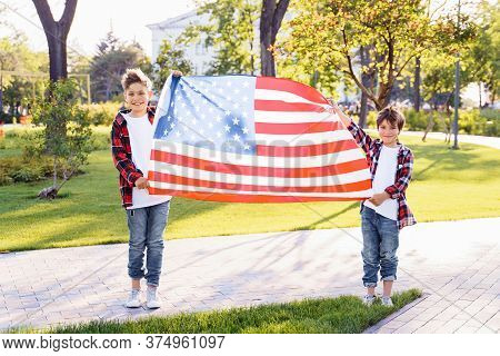 America's Usa Independence Day. Two Cute Brothers Guy Americans Standing In A City Park On Skateboar