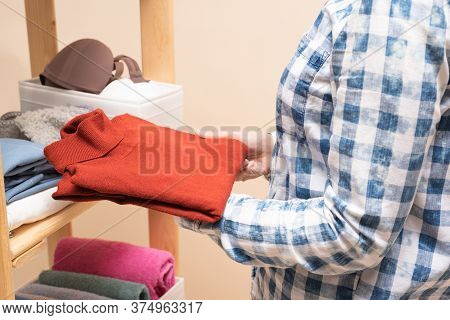 A Woman Is Placing A Clothes On The Rack Shelf In The Wardrobe Close Up.