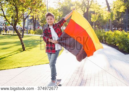 Guy Of 9 Years Old Riding Skateboard On Sunny Road In The Evening In The City Park. Holding Flutteri