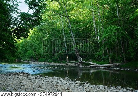 The Chagrin River In Northeast Ohio Flows At Summer Low Water Level At Dusk As Shadows Deepen
