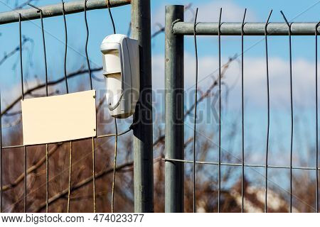 Wireless White Plastic Motion Detector On A Metal Temporary Fence Protecting A Construction Site Out