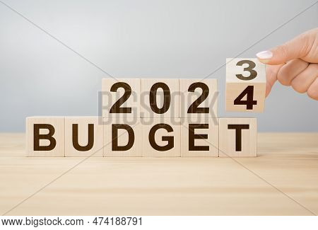 Business Concept Of Planning 2024. Businessman Flips Wooden Cube And Changes Words Budget 2023 To Bu