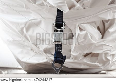 The Weight Belt Is Fastened To The Deck With A Ratchet Lock And Holds The Load Wrapped In A White Fi
