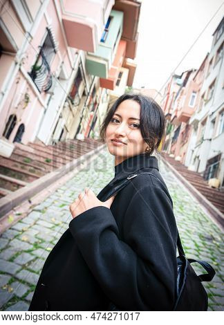 Omanian Girl In Black Looks To Camera In Scenic Balat District Turkey, Istanbul
