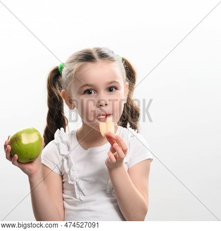 A Little Girl Is Holding One Apple And Chips On A White Background.