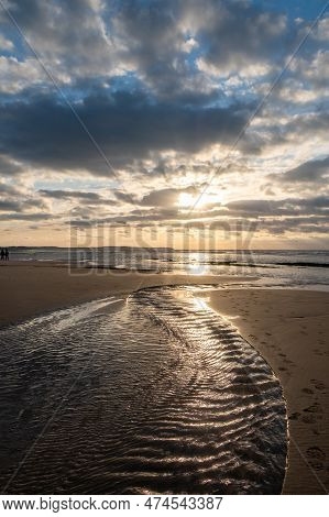 Sandy Beach At The Sea Under A Sky Painted With Clouds And A Golden Sun, Showing An Amazing Colorful