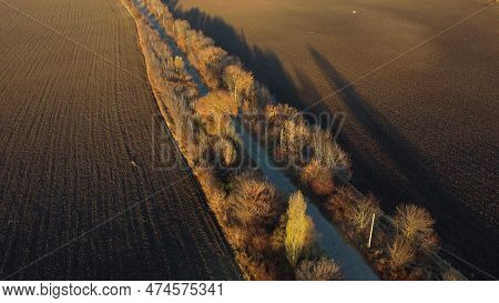 Beautiful Landscape View Old Asphalt Road With Trees And Shadows Between Large Plowed Agricultural F