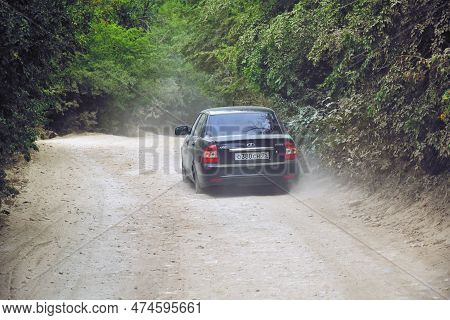 Dagestan, Russia - 20 July, 2022: Car Lada Priora Is Driving  On Full Of Dust Countryside Dirt Road.