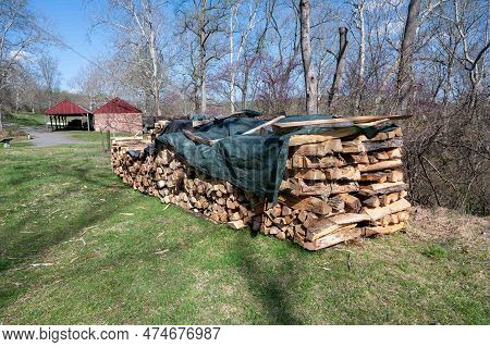 Rural Rustic Scene Of A Row Of Chopped And Stacked Cord Of Wood Cordwood With A Big Barn And Country