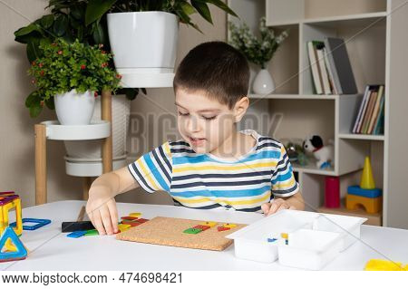 A Preschool Child Plays With A Mosaic, Builds Figures On A Board, Hammering Nails With A Hammer On M