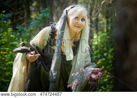 Adult Mature Woman 40-60 In A Green Long Fairy Dress In Forest. Photo Shoot In Style Of Dryad And Qu