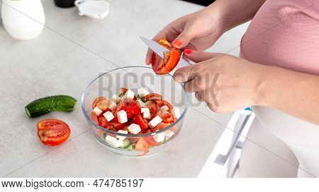 A Pregnant Girl Prepares A Vegetable Salad Of Cucumbers And Tomatoes. The Concept Of Nutrition Of Pr